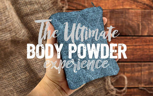Hand holding a sack sack body applicator.  Text over the image says The Ultimate Body Powder Experience.  Background shows a burlap sack and natural wood decking.